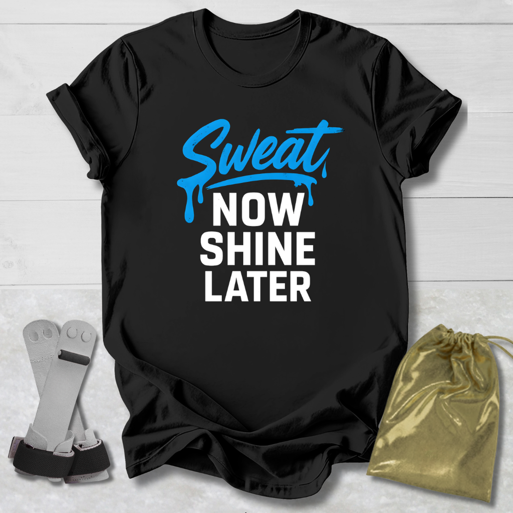 Black t-shirt with 'Sweat Now Shine Later' text, socks, and drawstring bag on a light wooden surface