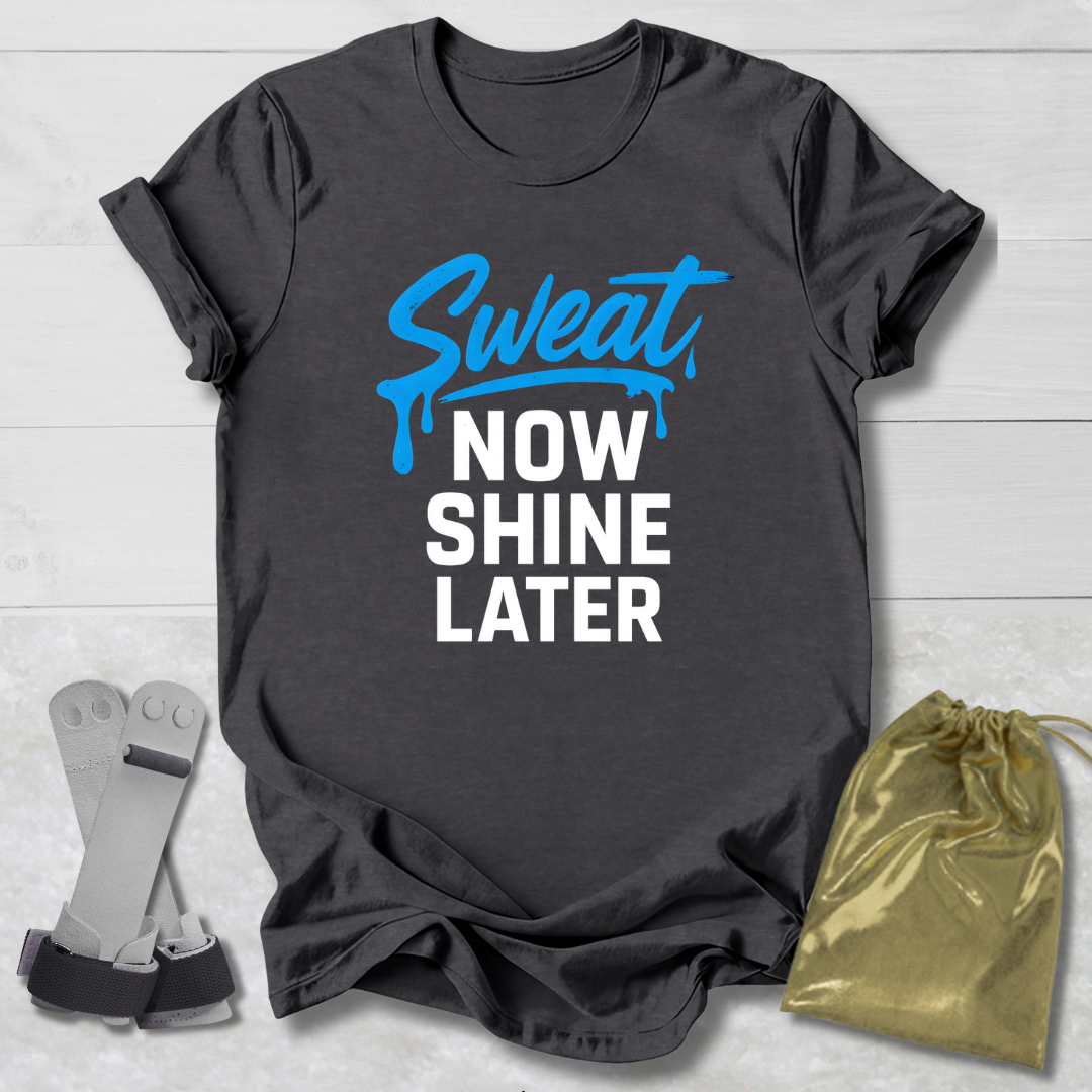 Dark gray t-shirt with 'Sweat Now Shine Later' text, socks, and drawstring bag on a light wooden surface.
