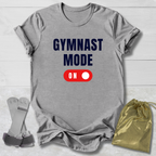 Gray t-shirt with 'GYMNAST MODE ON' text, socks, and drawstring bag on a light wooden surface