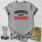 Gray t-shirt with 'PROGRESS over EXCUSES' text, socks, and drawstring bag on a light wooden surface