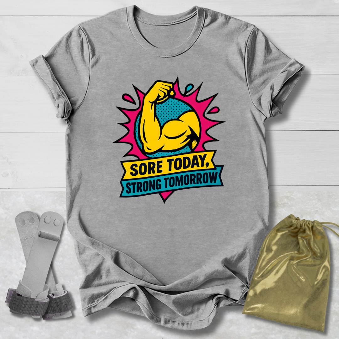 Gray t-shirt with a colorful graphic and text 'Sore Today, Strong Tomorrow' on a light wooden surface.