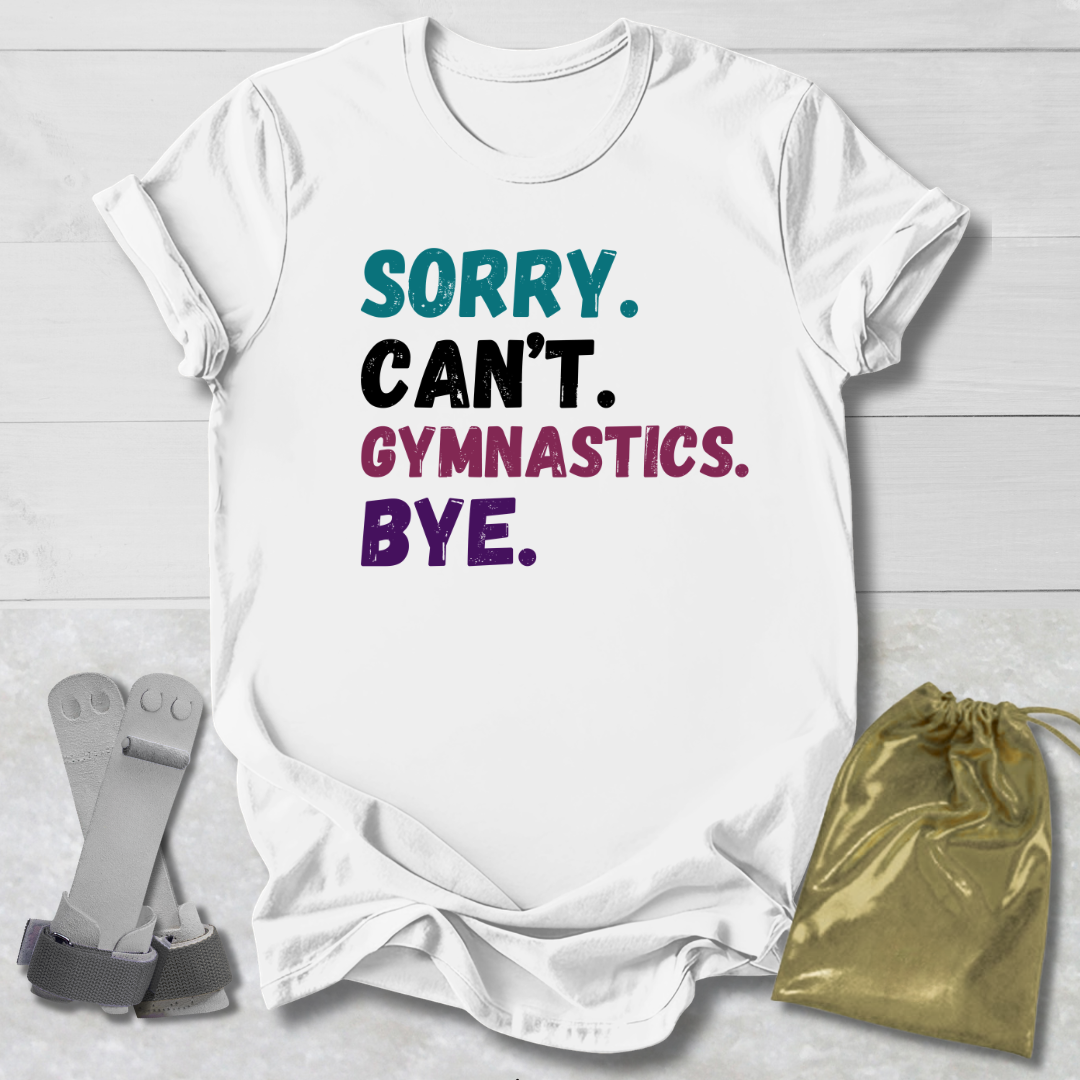 White t-shirt with colorful text 'Sorry. Can't. Gymnastics. Bye.' on a light wooden surface.