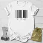 White t-shirt with barcode and 'GYMNAST' text, socks, and drawstring bag on a light wooden surface