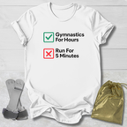 White t-shirt with 'Gymnastics For Hours' and 'Run For 5 Minutes' text, socks, and drawstring bag on a light floor.