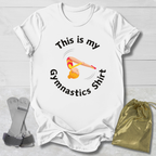 White t-shirt with gymnastics-themed design and accessories on a light wooden surface