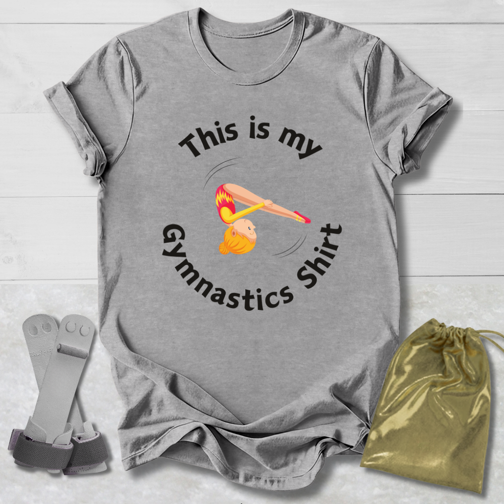 Gray t-shirt with gymnastics-themed design and accessories on a light wooden surface