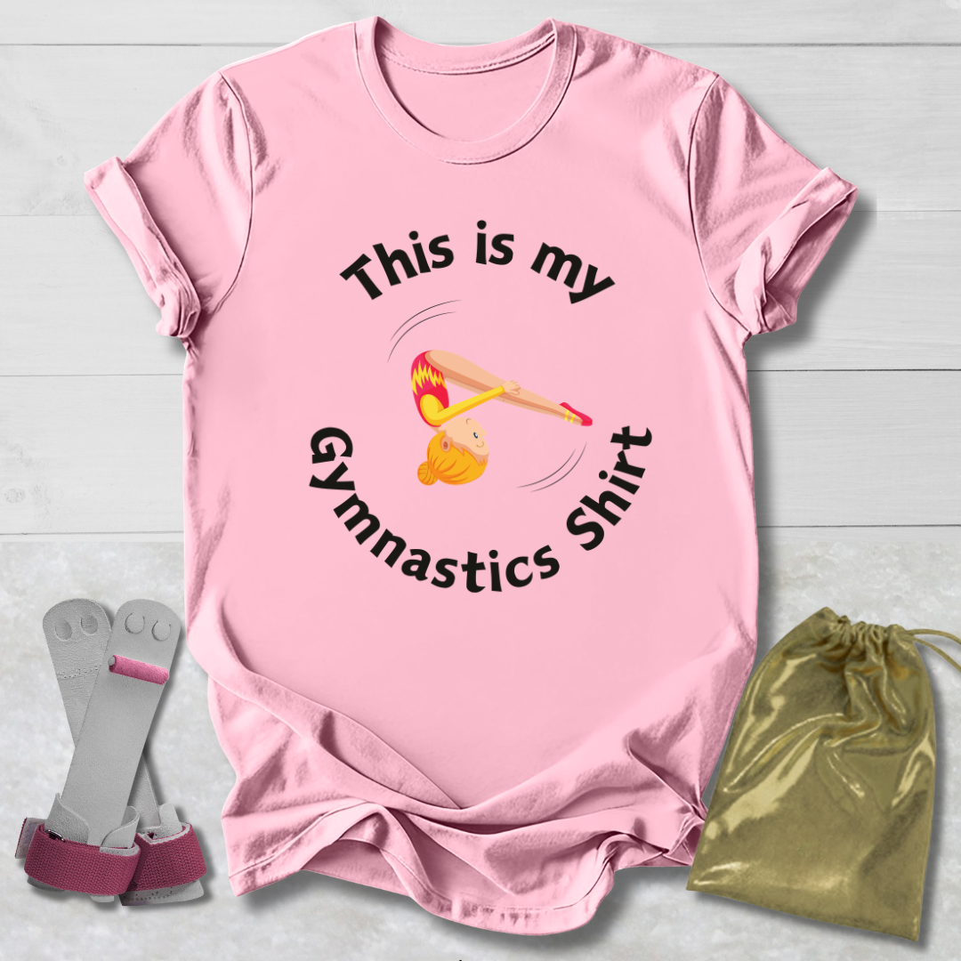 Pink t-shirt with gymnastics design and text, socks, and drawstring bag on a light wooden surface