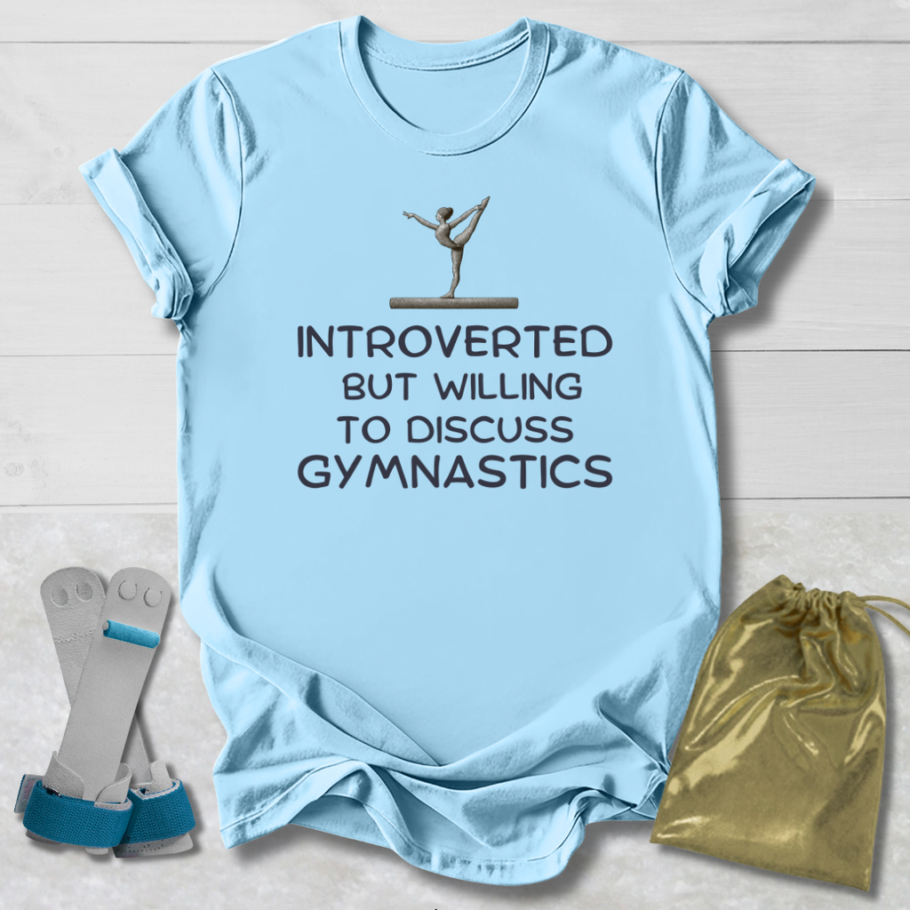 Light blue t-shirt with gymnastics-themed text and graphics on a wooden surface.