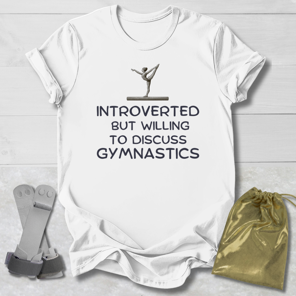 White t-shirt with gymnastics-themed text and graphics on a light wooden surface.