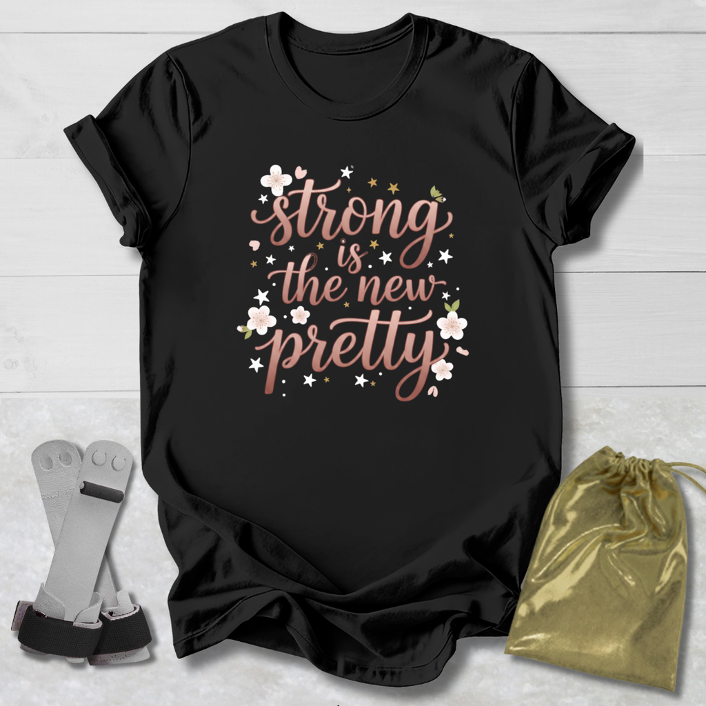 Black t-shirt with 'strong is the new pretty' text on a wooden surface with socks and a drawstring bag.