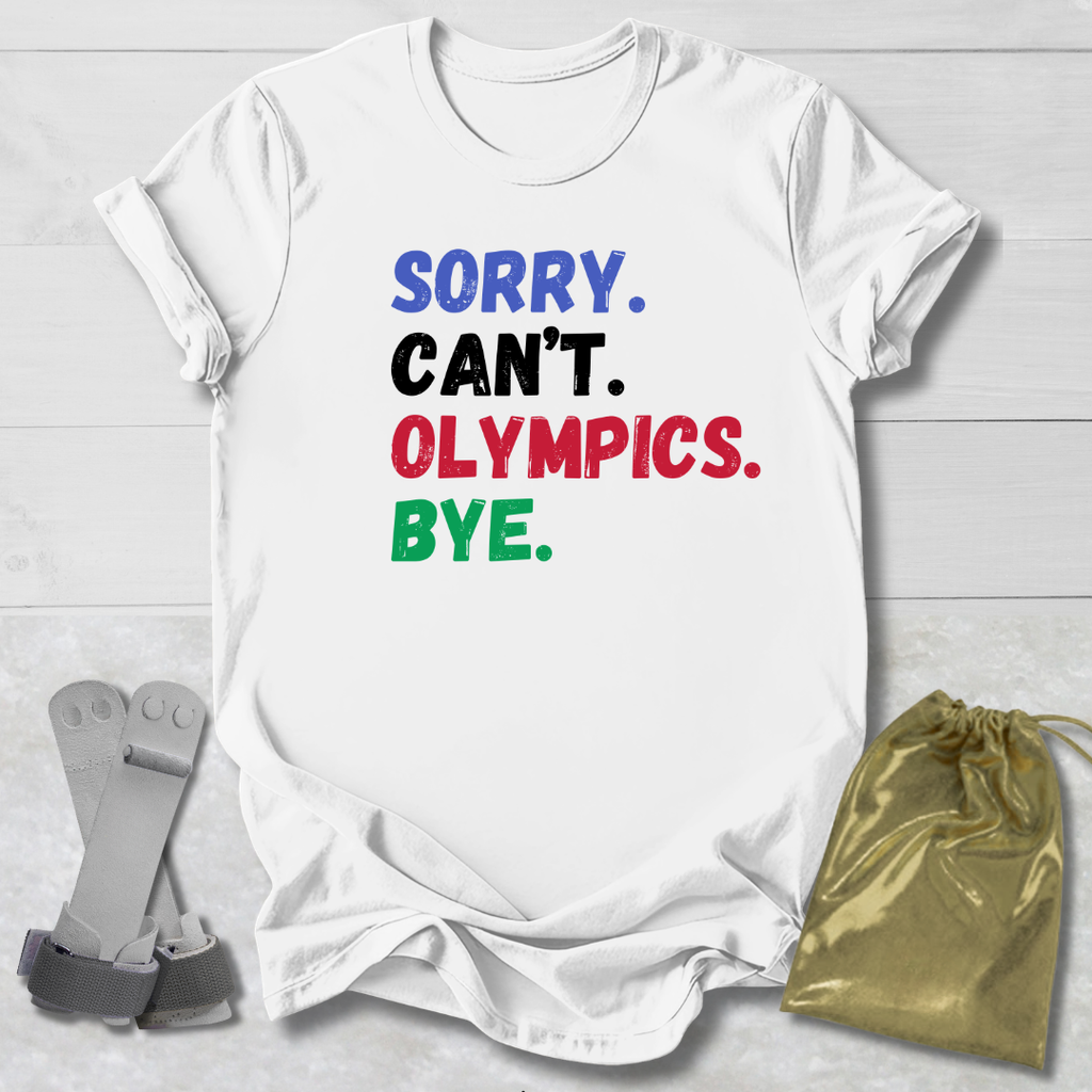 White t-shirt with colorful text 'SORRY. CAN'T. OLYMPICS. BYE.' on a light wooden surface.