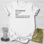 White t-shirt with 'Gymnast' definition text, socks, and drawstring bag on a light wooden surface