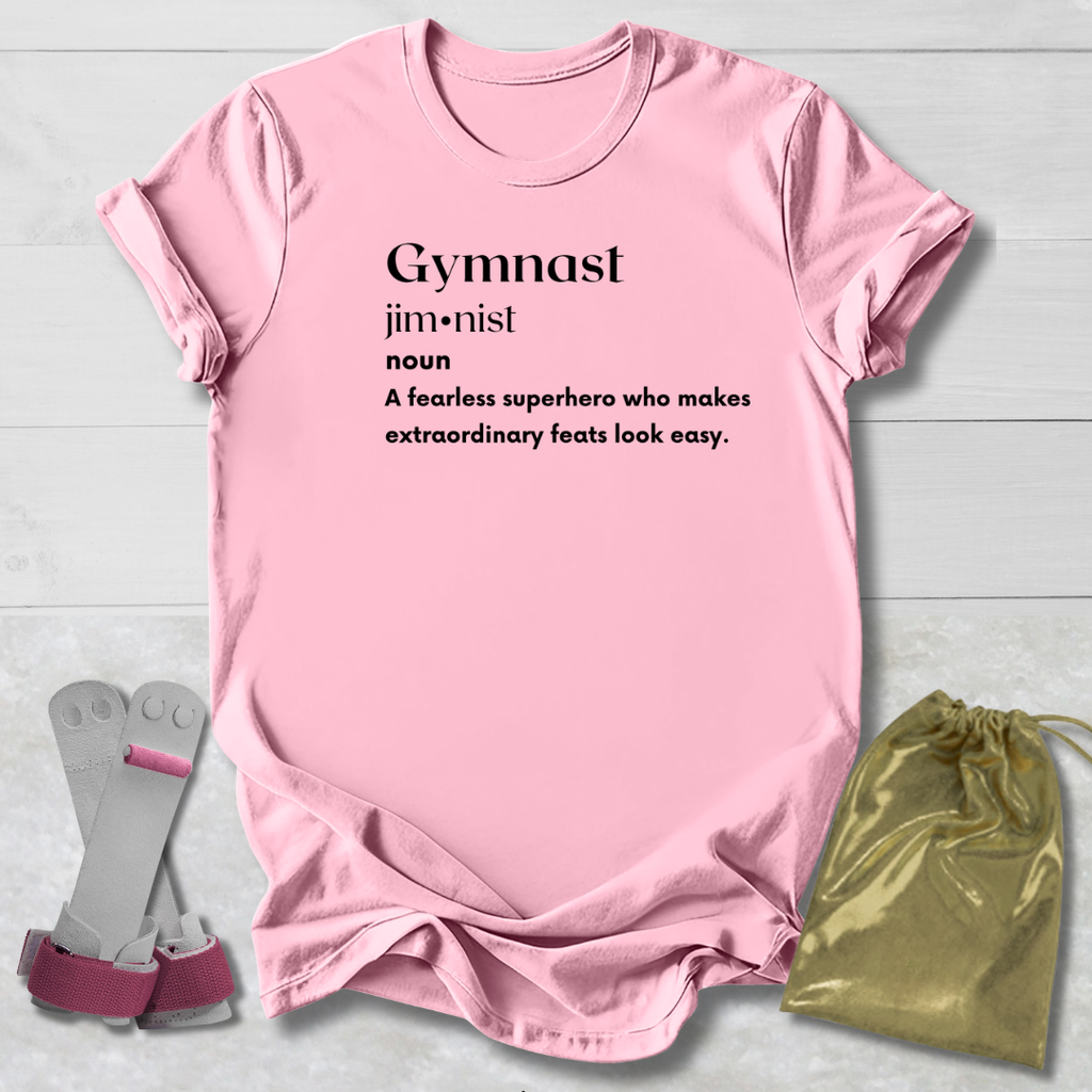 Pink t-shirt with 'Gymnast' definition text, socks, and drawstring bag on a light wooden surface