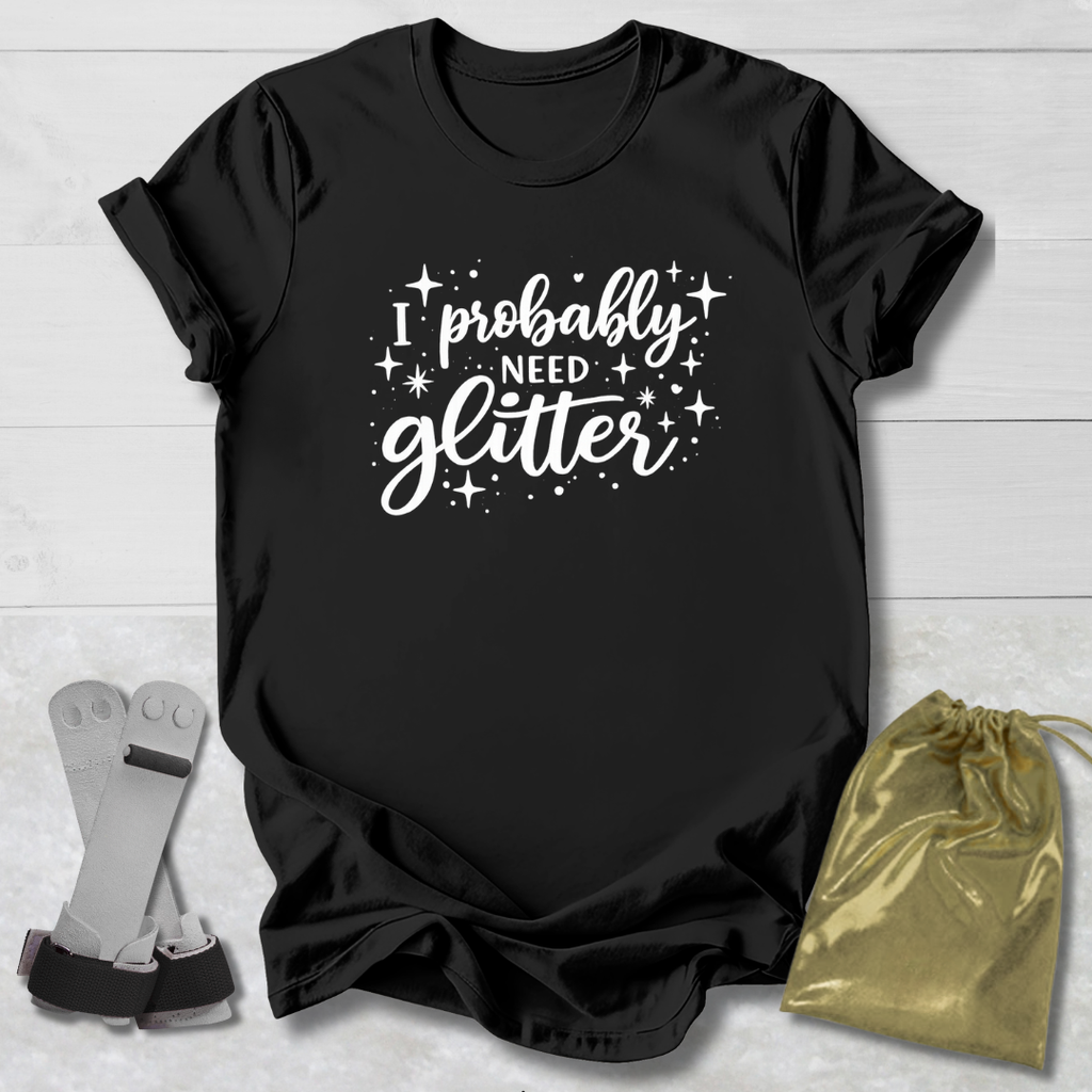 Black t-shirt with 'I probably need glitter' text on a light wooden surface with socks and a drawstring bag.