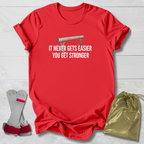 Red t-shirt with motivational gymnastics quote, socks, and drawstring bag on a light wooden surface