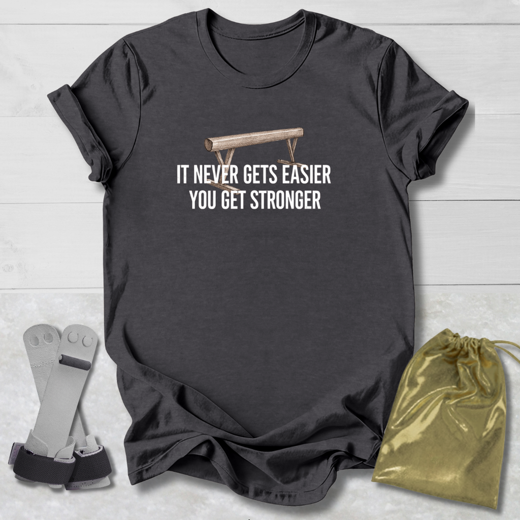 Dark gray t-shirt with motivational gymnastics quote, socks, and drawstring bag on a light wooden surface