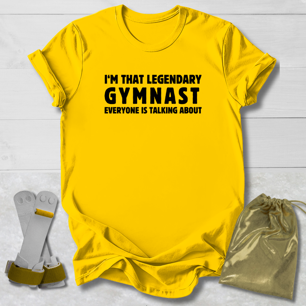 Yellow t-shirt with text 'I'm that legendary gymnast everyone is talking about' on a light wooden surface.