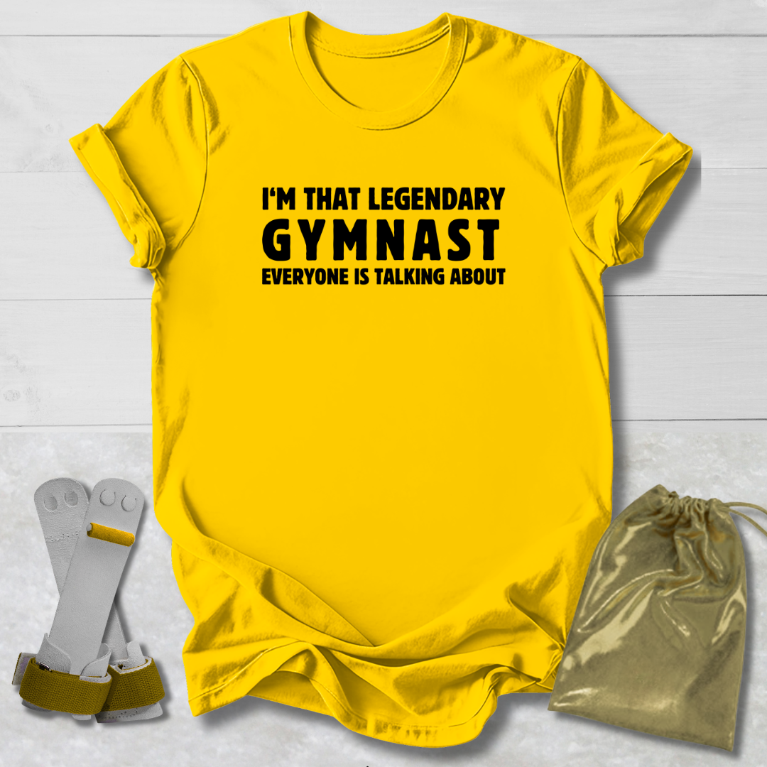 Yellow t-shirt with text 'I'm that legendary gymnast everyone is talking about' on a light wooden surface.