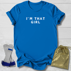 Blue t-shirt with 'I'm That Girl' text, socks, and a drawstring bag on a light wooden surface.