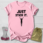 Pink gymnastics gymnast t-shirt with 'JUST STICK IT.' text and silhouette, socks, and drawstring bag on a light wooden surface.
