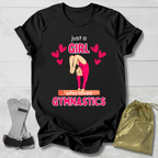 Black t-shirt with gymnastics-themed Just a Girl Who Loves Gymnastics design on a light wooden surface.