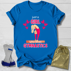 Blue t-shirt with gymnastics-themed Just a Girl Who Loves Gymnastics design on a wooden surface with socks and a drawstring bag.