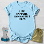 Light blue t-shirt with 'Life happens. Gymnastics helps.' text, socks, and drawstring bag on a light wooden surface.