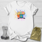 White t-shirt with colorful graphic design on a light wooden surface, accompanied by gray socks and a gold drawstring bag.