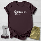 Maroon t-shirt with 'Gymnastics Life' text, socks, and drawstring bag on a light wooden surface