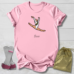 Pink t-shirt with a graphic of a gymnast and the word 'Floor', accompanied by gray socks and a gold drawstring bag on a light wooden surface.