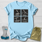 Light blue t-shirt with gymnastics-themed graphic and accessories on a wooden surface