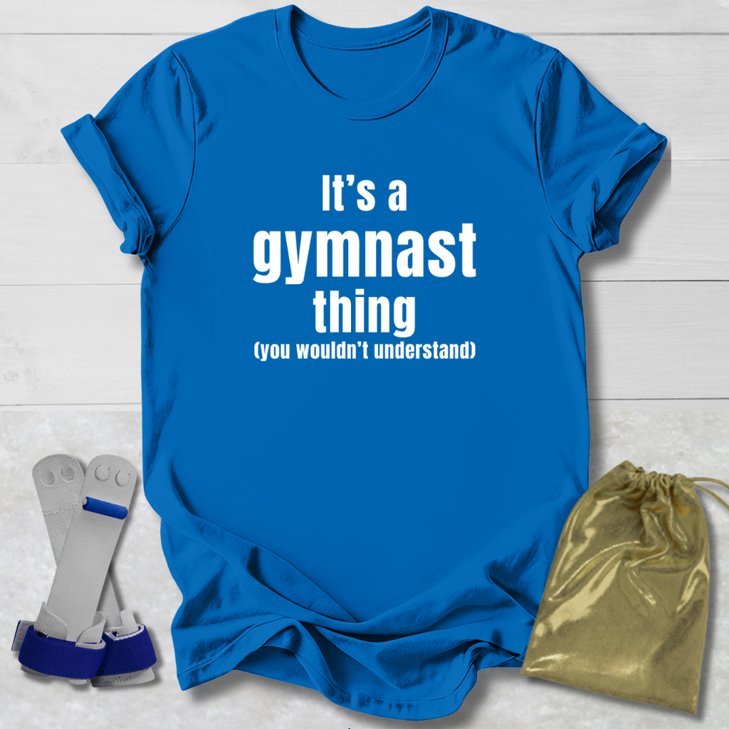 Blue t-shirt with 'It's a gymnast thing (you wouldn't understand)' text, socks, and drawstring bag on a light wooden surface.