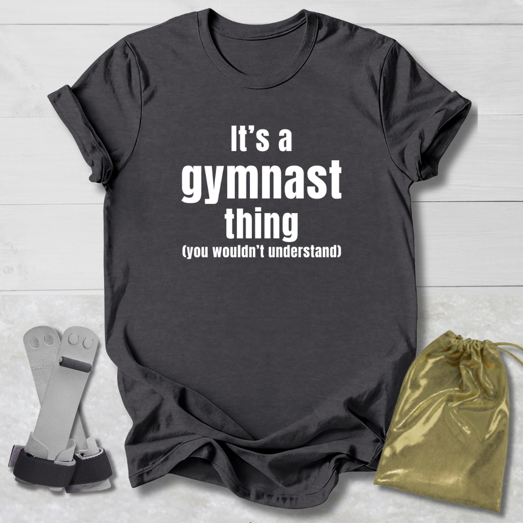 Maroon t-shirt with 'It's a gymnast thing (you wouldn't understand)' text, socks, and drawstring bag on a light wooden surface.