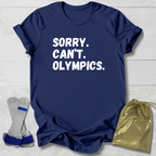 Navy blue t-shirt with 'Sorry. Can't. Olympics.' text, socks, and drawstring bag on a light wooden surface.