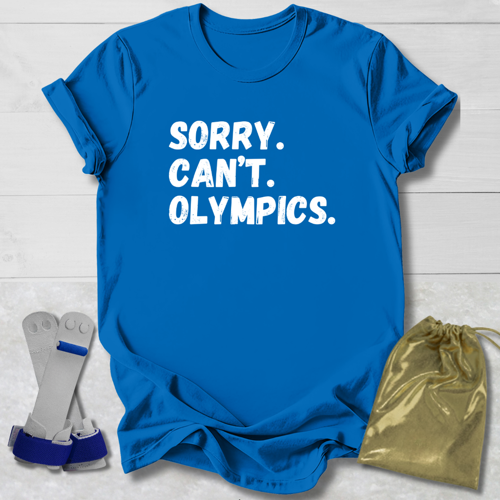Blue t-shirt with 'SORRY. CAN'T. OLYMPICS.' text, socks, and drawstring bag on a light wooden surface