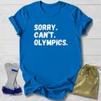 Blue t-shirt with 'SORRY. CAN'T. OLYMPICS.' text, socks, and drawstring bag on a light wooden surface