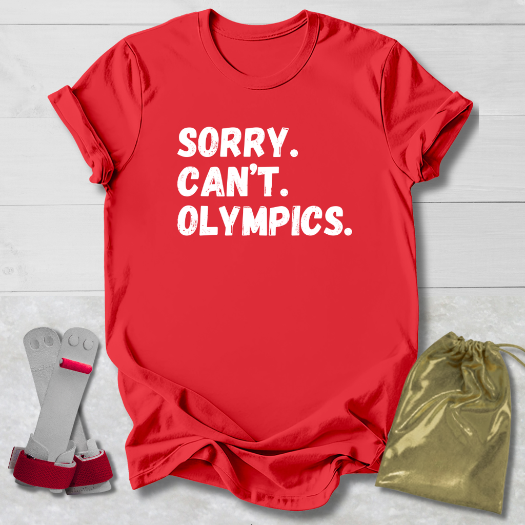 Red t-shirt with 'SORRY. CAN'T. OLYMPICS.' text, socks, and drawstring bag on a light wooden surface.