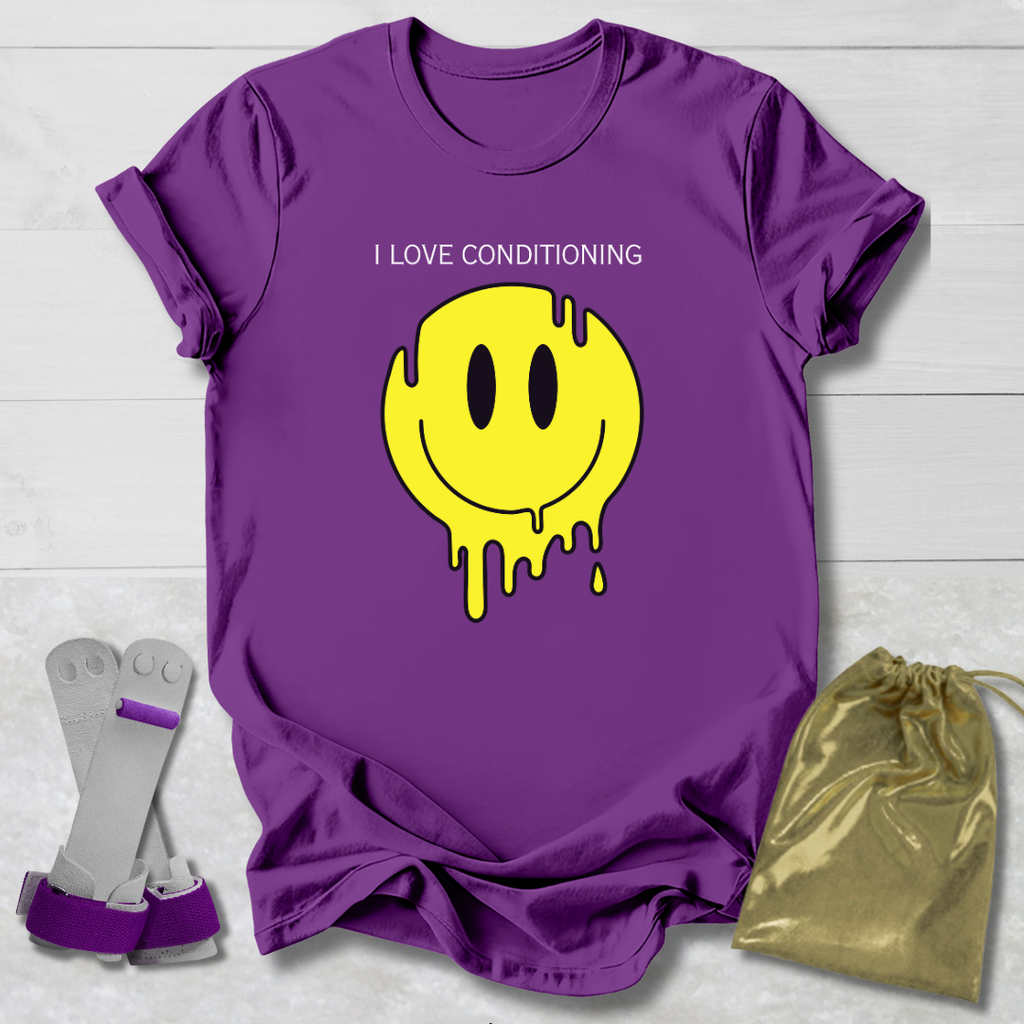 Purple t-shirt with yellow smiley face graphic and text, socks, and drawstring bag on a light wooden surface.