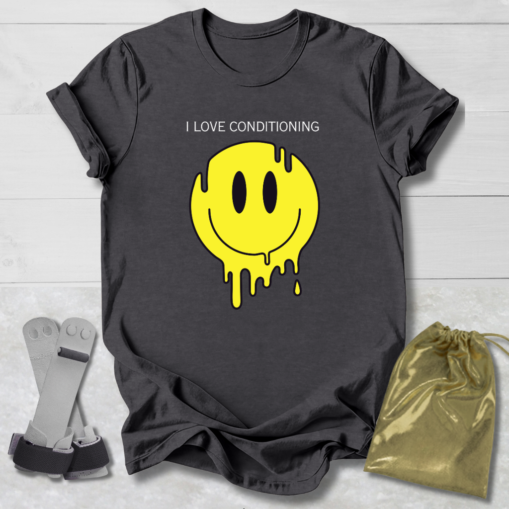Gray t-shirt with yellow smiley face graphic and text 'I LOVE CONDITIONING' on a light wooden surface.