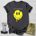 Gray t-shirt with yellow smiley face graphic and text 'I LOVE CONDITIONING' on a light wooden surface.