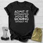 Black t-shirt with text 'Admit it, gymnastics would be boring without me' on a light wooden surface.