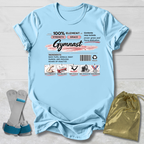 Light blue t-shirt with gymnast-themed graphics and text on a wooden surface.