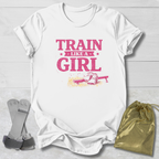 White t-shirt with 'Train Like a Girl' text and graphics on a light wooden surface.