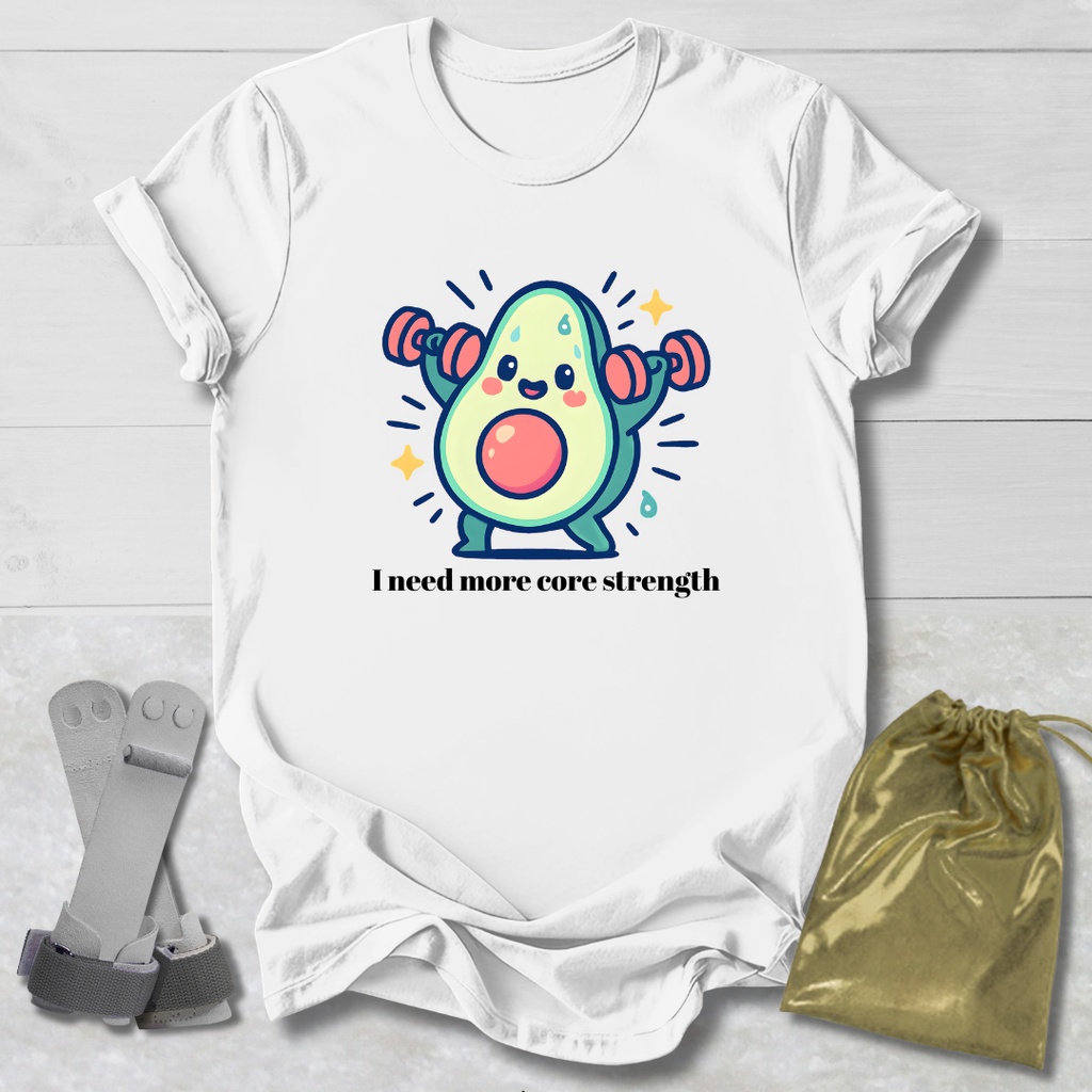 White t-shirt with a cartoon avocado lifting weights and text 'I need more core strength' on a light wooden surface.