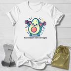 White t-shirt with a cartoon avocado lifting weights and text 'I need more core strength' on a light wooden surface.
