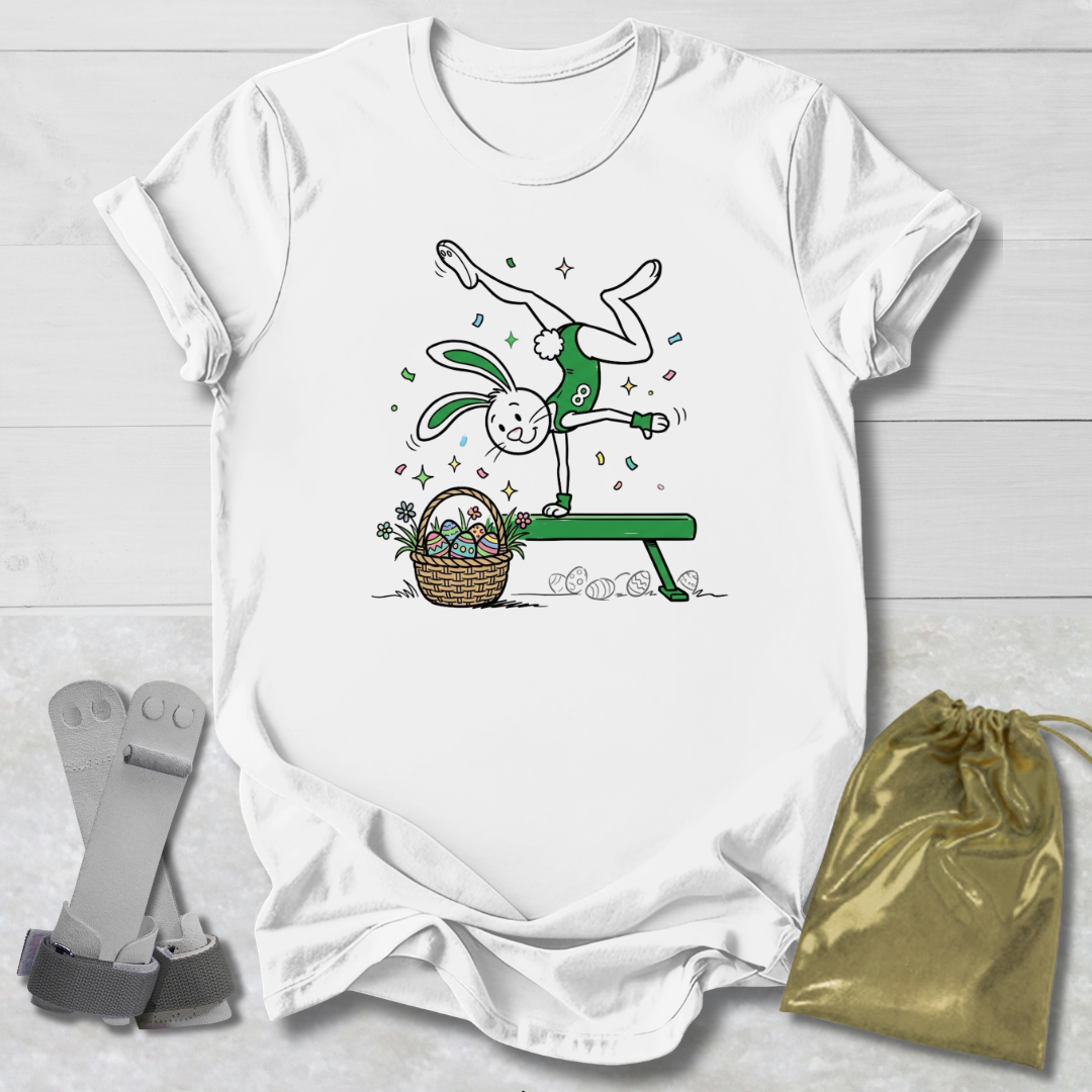 White t-shirt with a cartoon design of a rabbit on a bench with a basket, socks, and a drawstring bag on a light wooden surface.