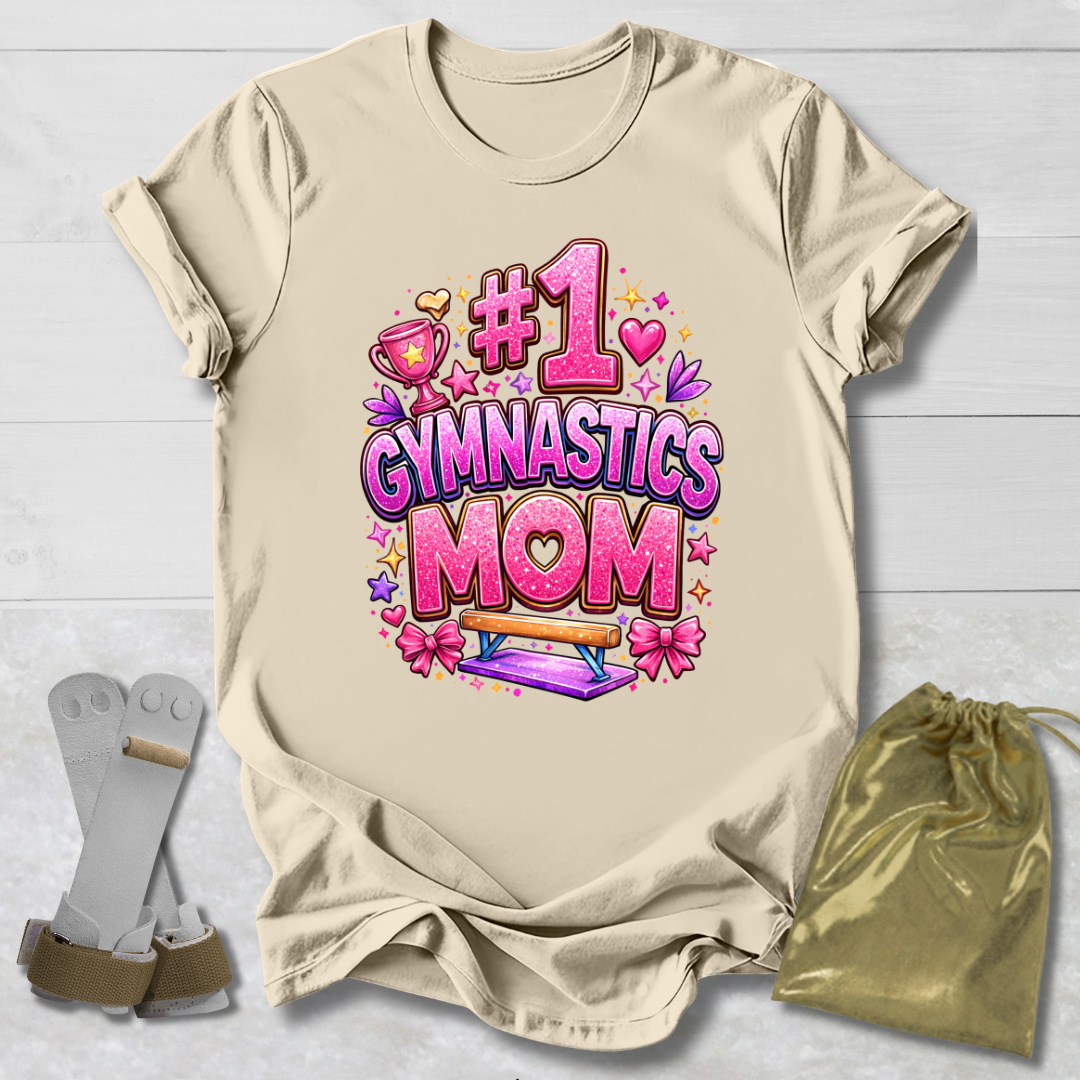 Beige t-shirt with '#1 Gymnastics Mom' text and graphics on a light wooden surface.