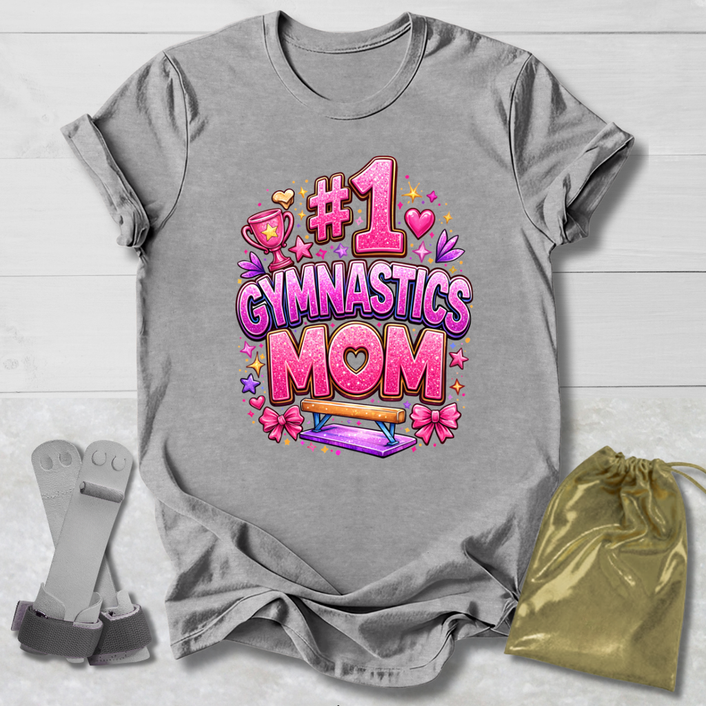 Gray t-shirt with '#1 Gymnastics Mom' design on a light wooden surface with socks and a drawstring bag.