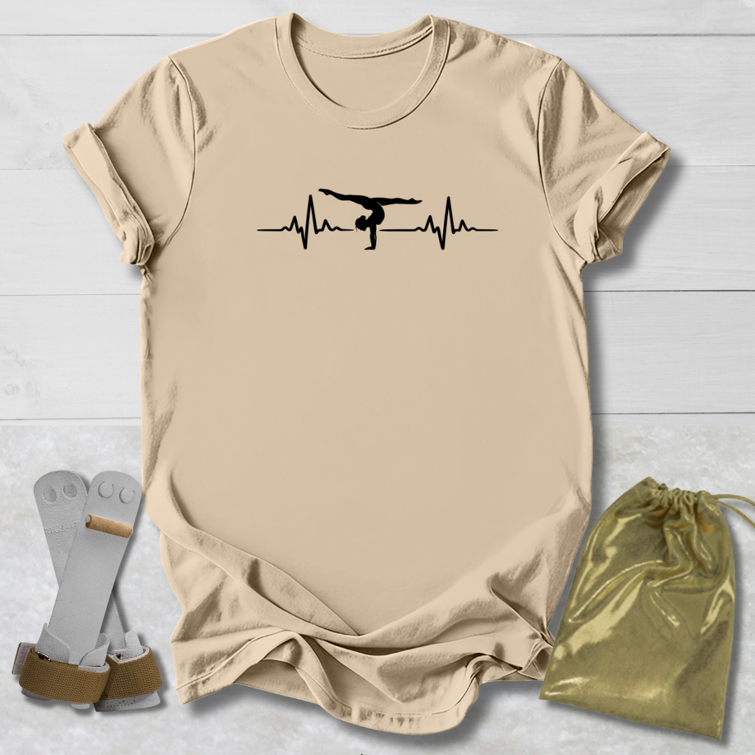 Beige t-shirt with a graphic  gymnast heartbeat design, socks, and a drawstring bag on a light wooden surface.
