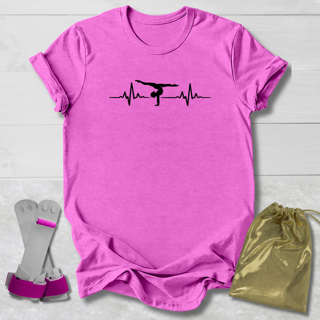 Pink t-shirt with a graphic  gymnast heartbeat design, socks, and a drawstring bag on a light wooden surface.